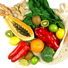 A colorful bouquet of fruits and vegetables in a mesh canvas bag.