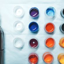 Photograph of the end of a tattoo gun and pots of different colored ink on a napkin.