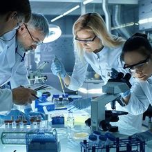 Team of Medical Research Scientists Collectively Working on a New Generation Experimental Drug Treatment. Laboratory Looks Busy, Bright and Modern.