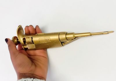 Hand holding a golden pipette.