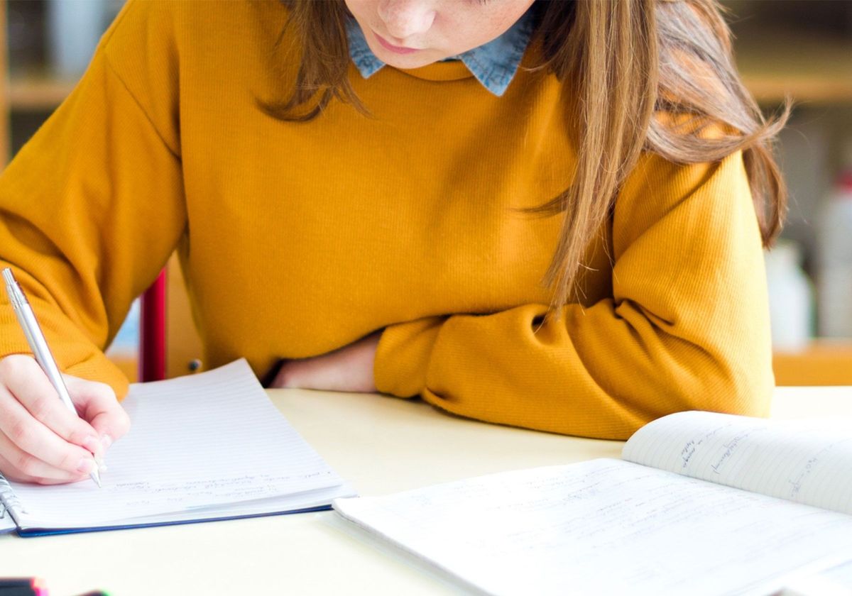 A person sitting in a laboratory writing notes with a pen in a notebook.