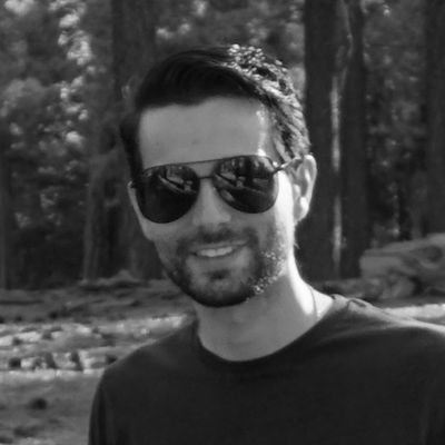 black and white image of young man in sunglasses with trees in background