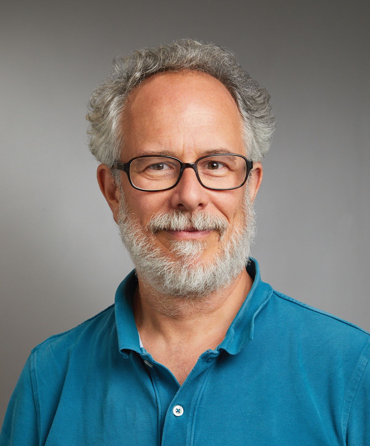 A man wear a blue polo shirt and glasses.