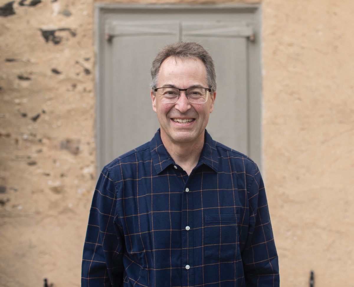 A man wears a plaid shirt and glasses.