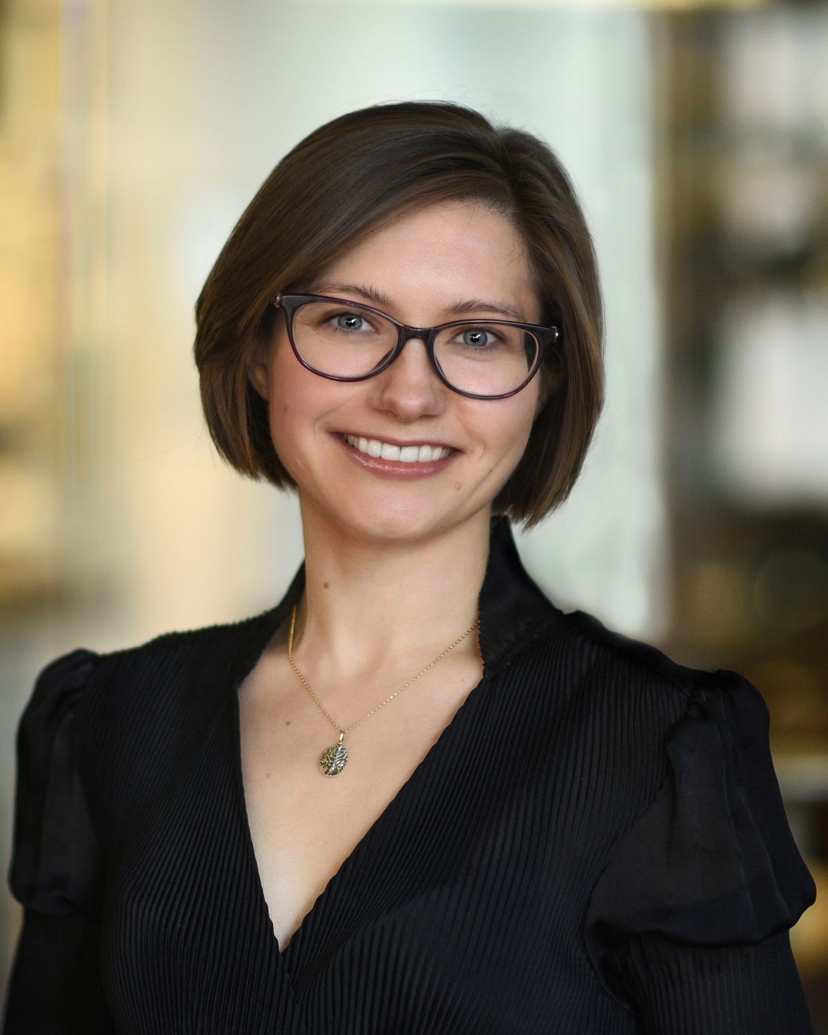 Image of Olga Dudchenko, a molecular geneticist at Baylor College of Medicine, studies how genomes fold in 3D in modern and nonmodern model species. She wears glasses and a black top as she smiles at the camera.