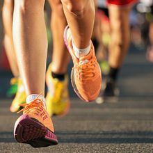 The feet of several runners wearing brightly colored shoes.