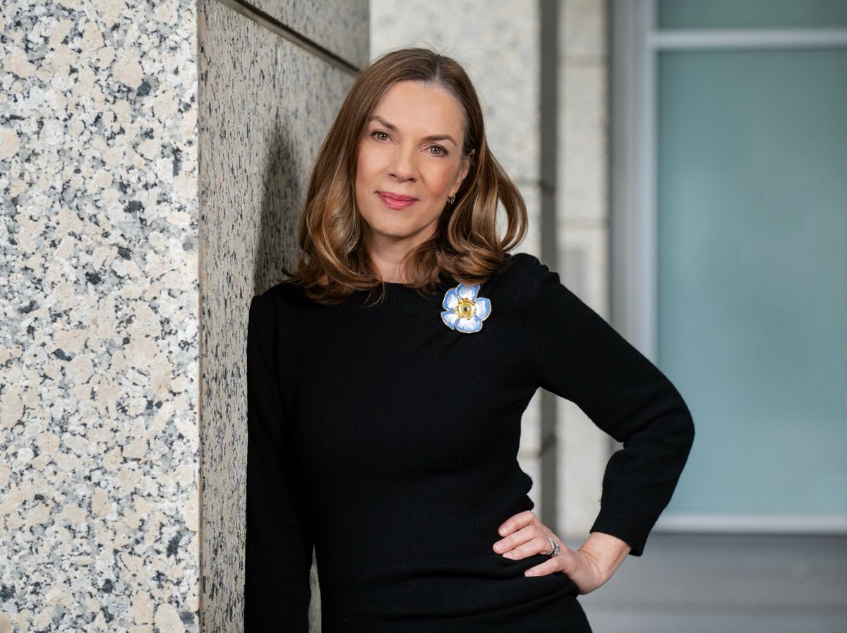 A woman in a black shirt with a flower on it smiles at the camera.