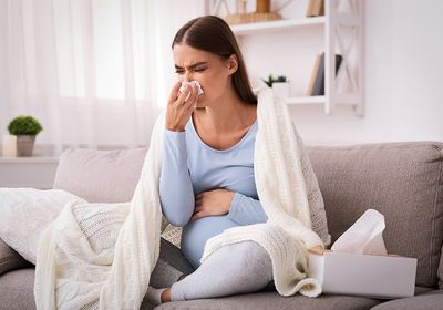 A pregnant woman blowing her nose.