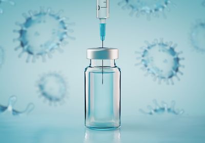 A syringe inserted into a vial of vaccine.