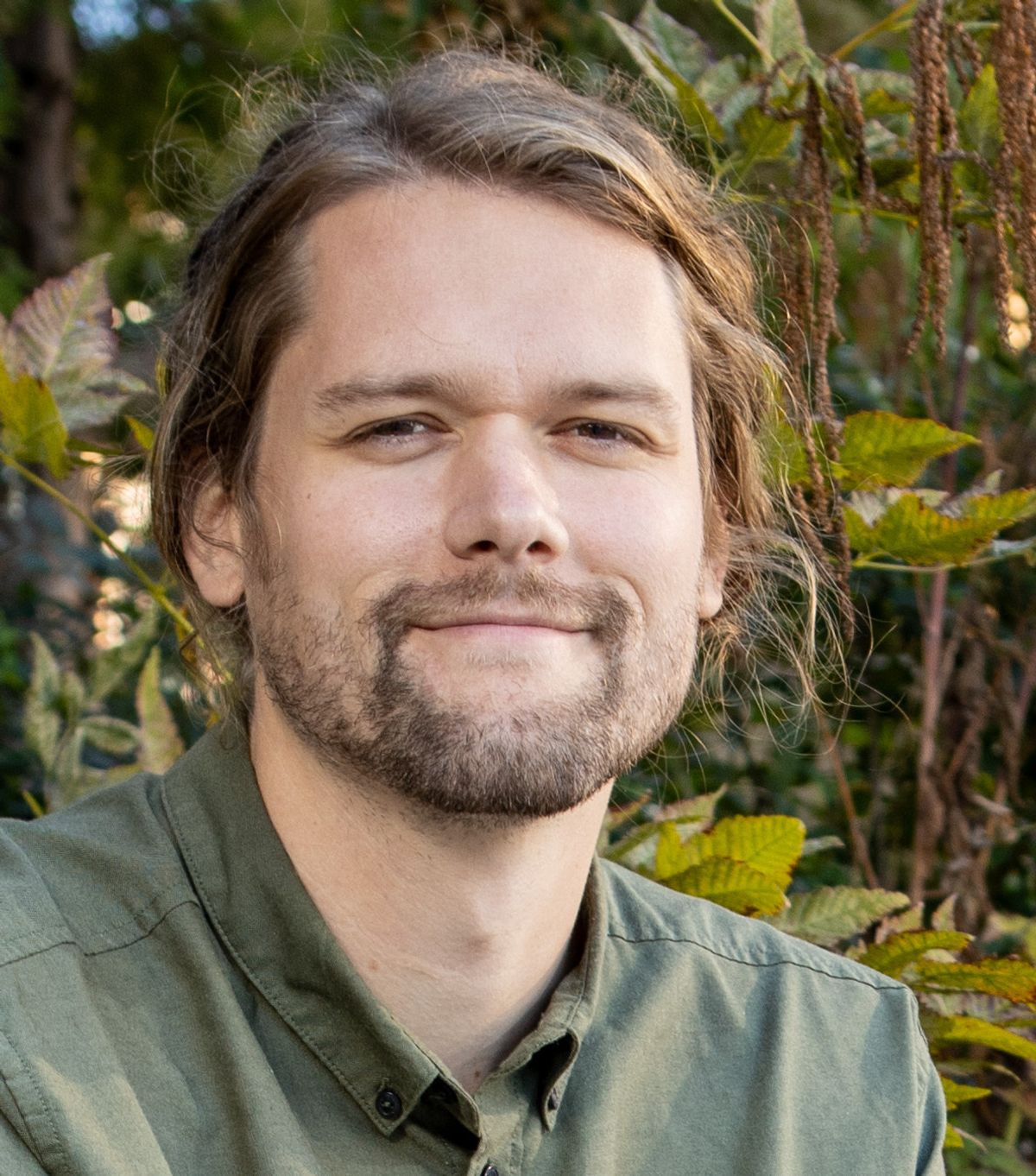 A headshot of Jeff Nivala, positioned in front of vegetation.