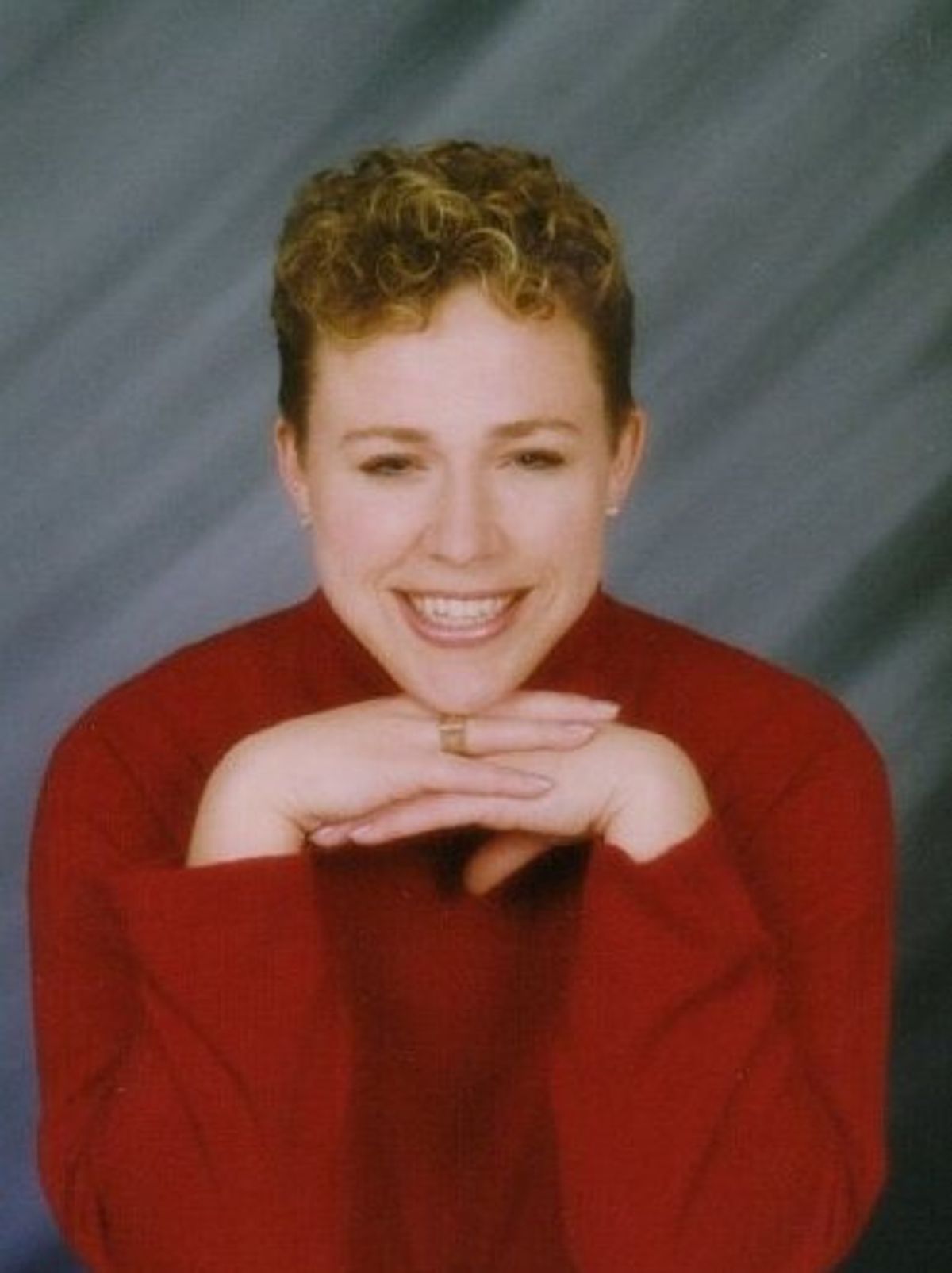 Photograph of a Julia Darby, currently a private tutor for school districts in Iowa and Illinois, learned that her convenient protein tags may have done more than she bargained for. She is wearing a red shirt and smiles at the camera with her hands folded under her chin. 