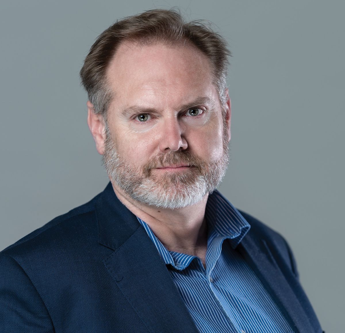 A man wears a blue shirt and jacket.