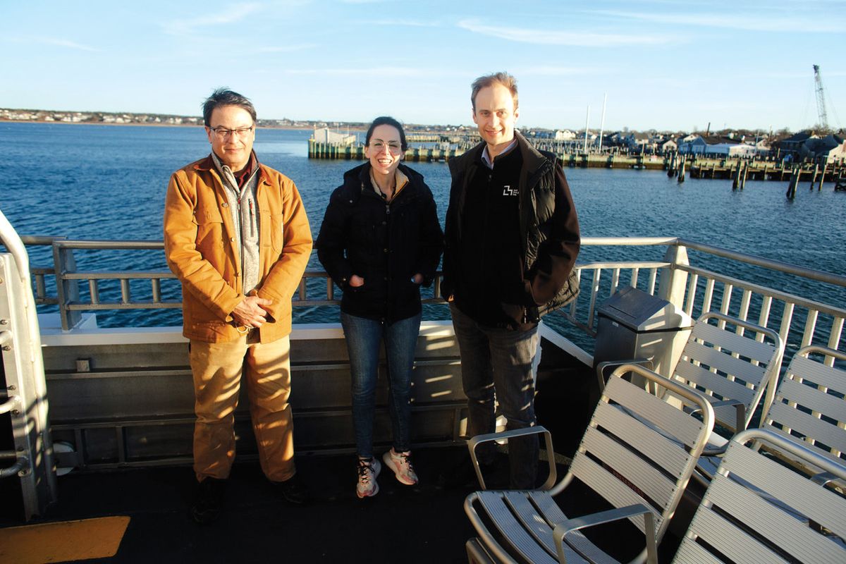 Sam Telford III, Joanna Buchthal, and Kevin Esvelt stand outside on a dock on a sunny day.