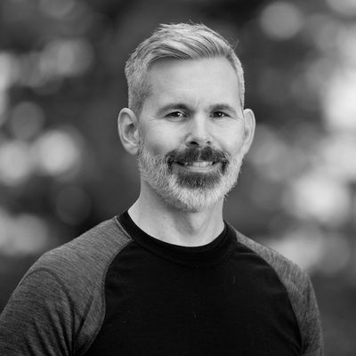 A black and white headshot of Andrew Carstens