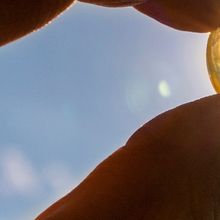 A hand holding a pill against sunlight.