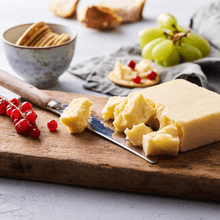 A block of cheddar cheese pictured here with various accompaniments.&nbsp;